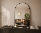 Arched black metal wall mirror above a dark console table