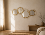 Four-circle gold metal wall mirror spanning a pale plaster wall